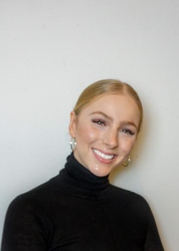 Woman in black turtleneck smiling with a white background